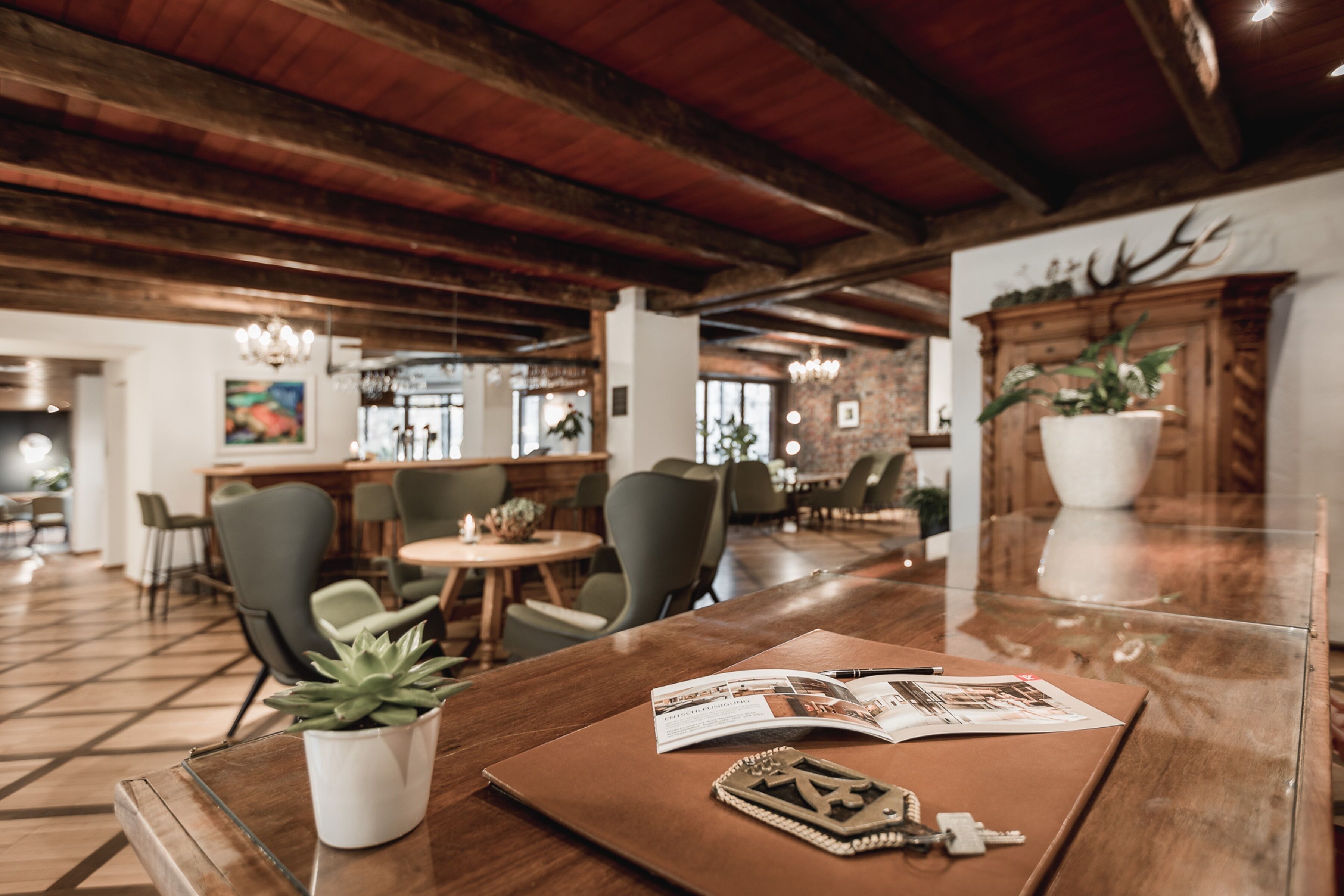 Une table en bois sur laquelle se trouvent un magazine, des clés et une plante dans un pot blanc.