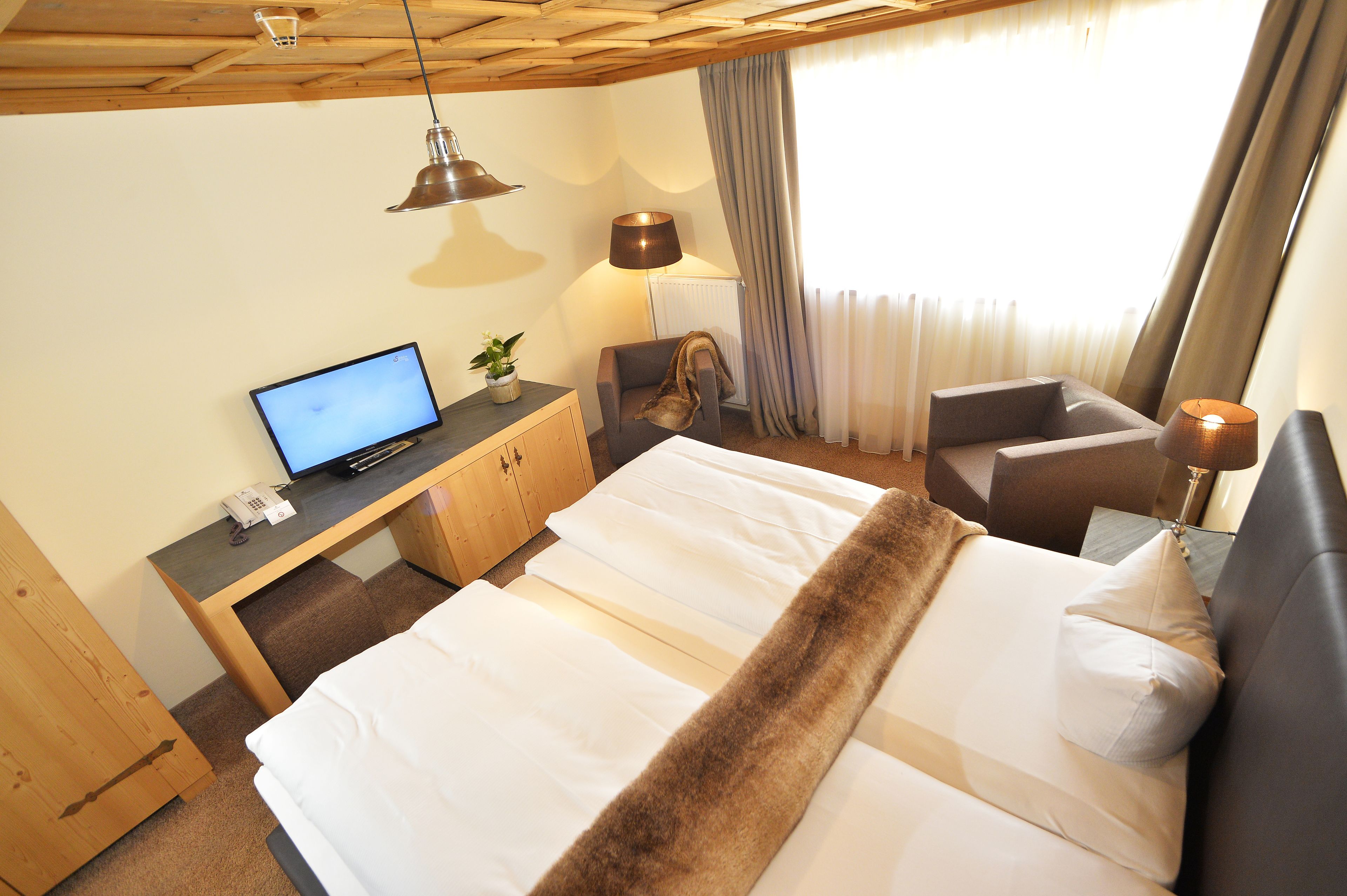 Una habitación de hotel con una cama, un escritorio con una computadora, una silla y una lámpara.