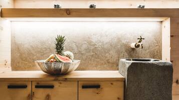 A wooden cabinet with a bowl of fruit and a stone sink.