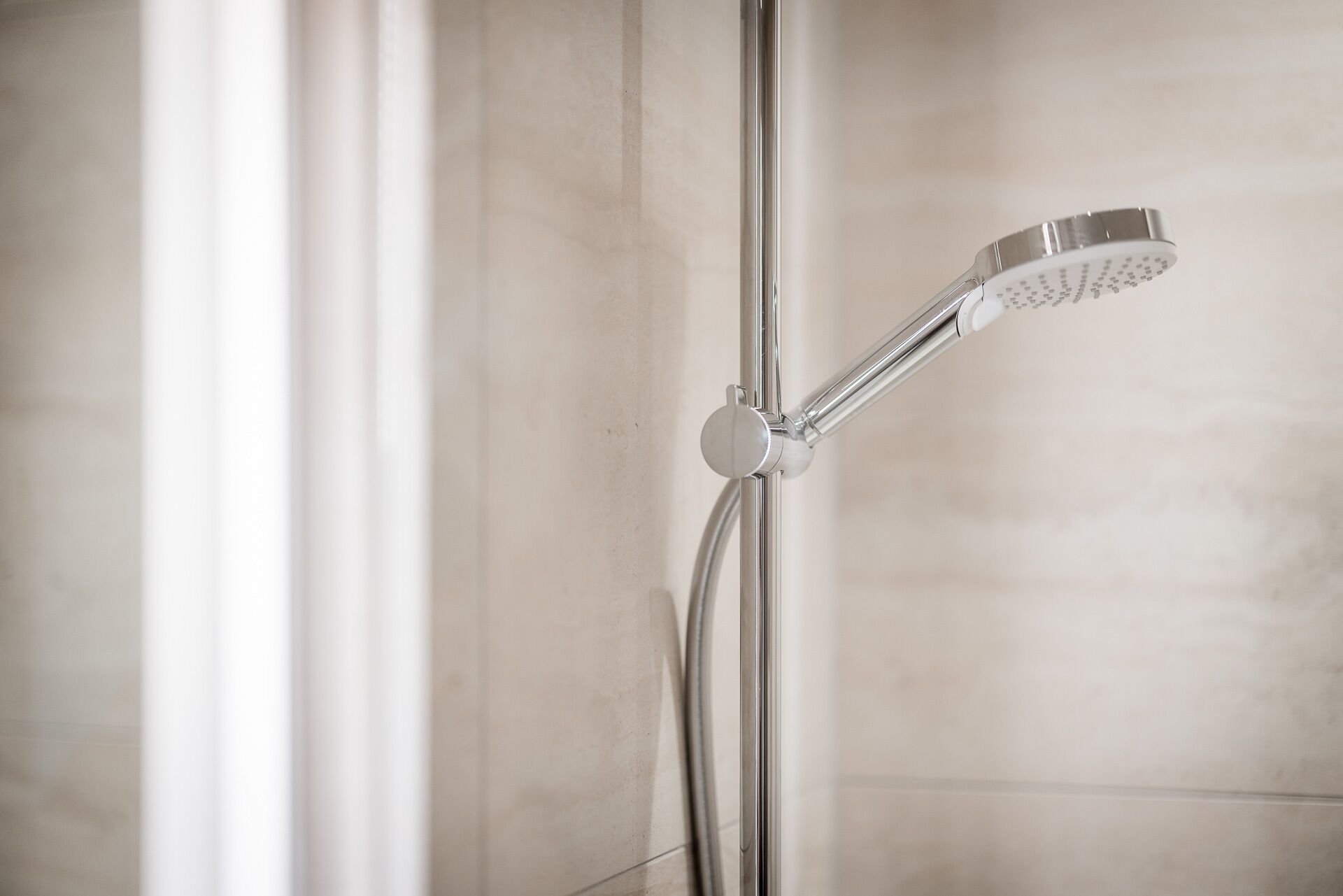 Une douche moderne dotée d’un pommeau de douche à main et d’un flexible.