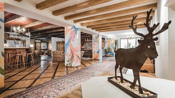 A spacious interior with wooden beams, a large decorative moose, and colorful abstract art on pillars.