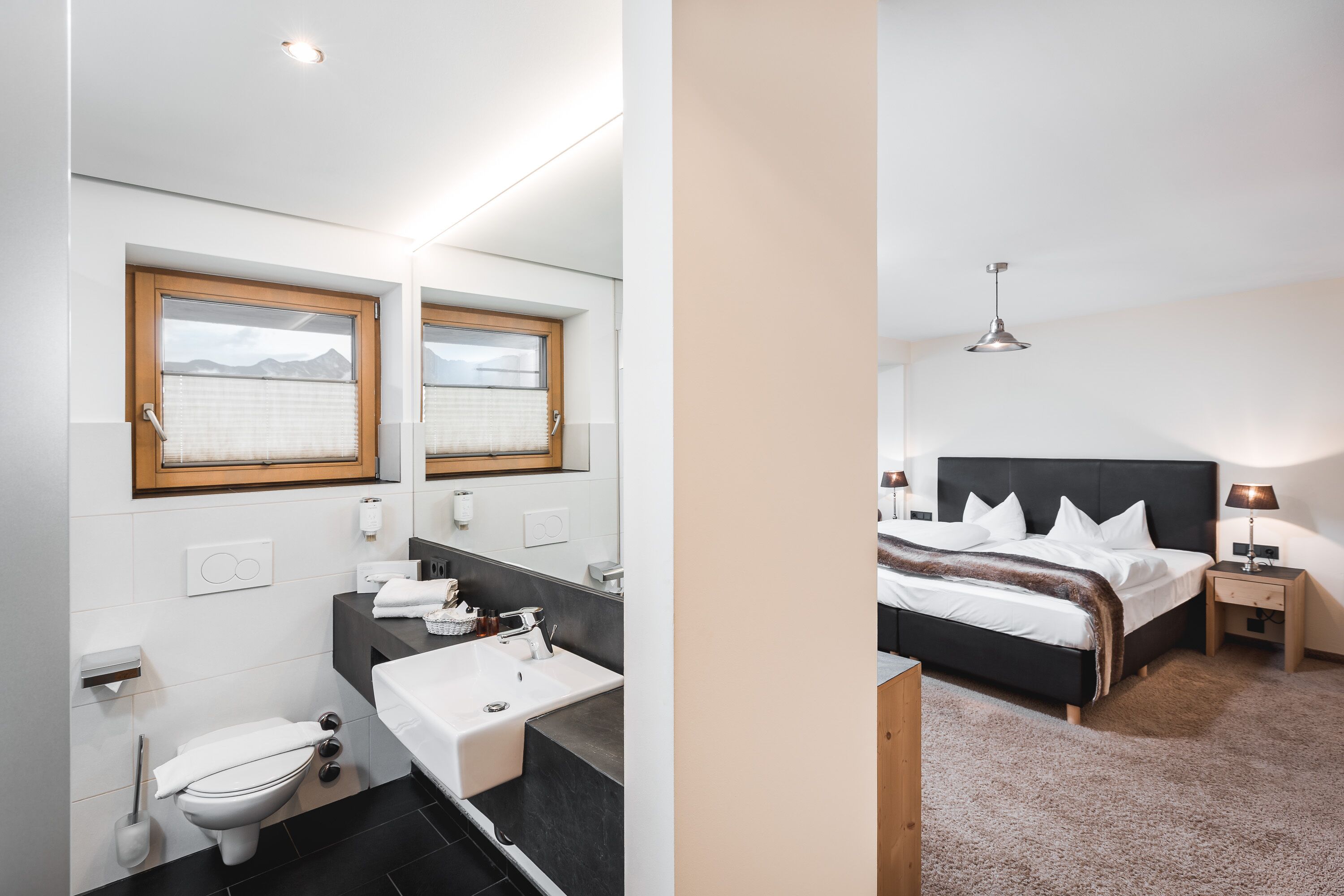 A modern bathroom with a toilet, sink, and mirror.