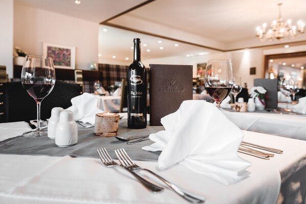 A well-set dining table with wine glasses, a bottle of wine, salt and pepper shakers, and a menu box. - SeeFelds Bed & Breakfast (Seefeld in Tirol)
