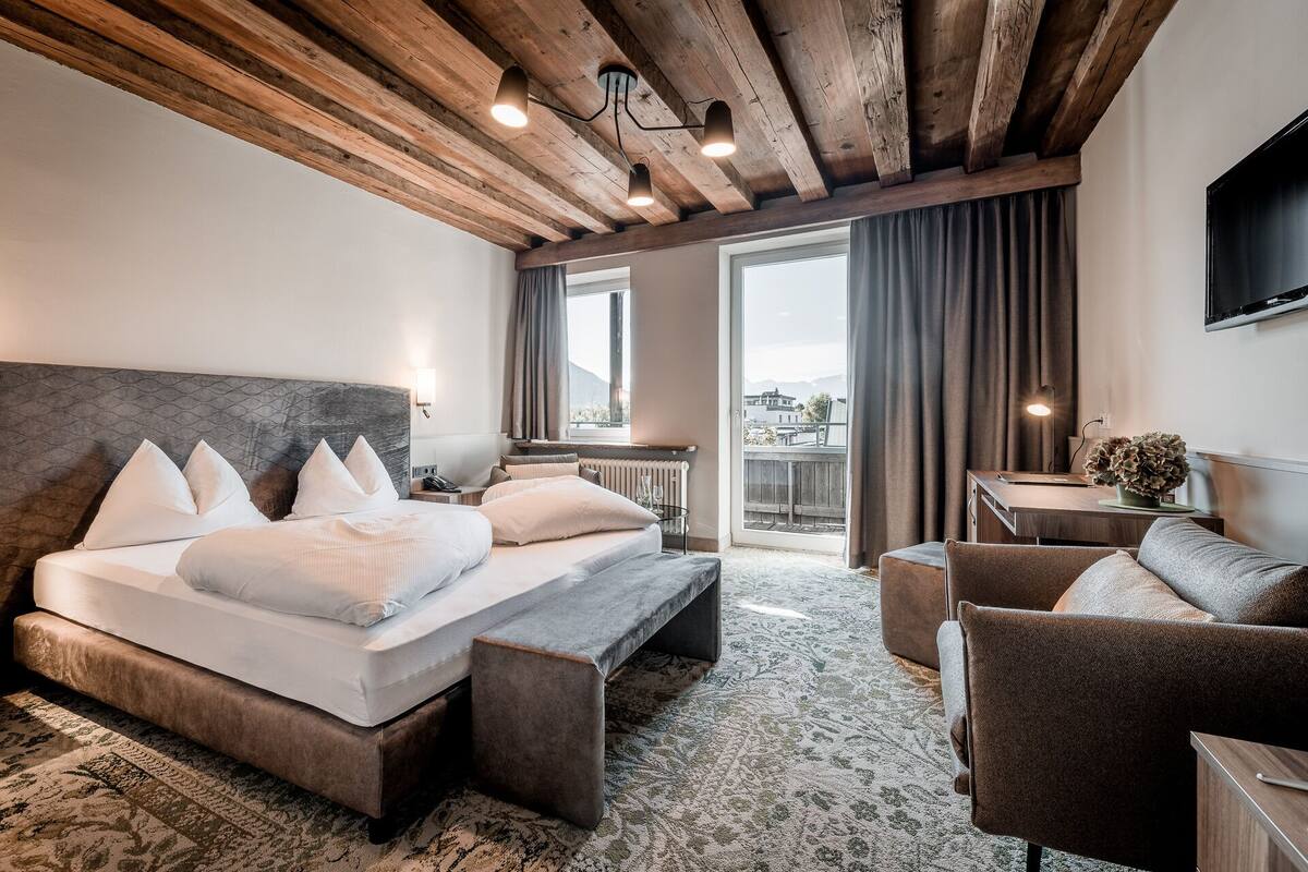 A hotel room with a large bed, a sofa, a small table, and a TV.