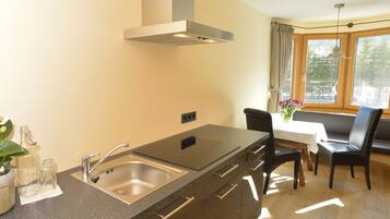 A kitchen with a stainless steel sink, a built-in oven, and a dining area with a table and chairs.