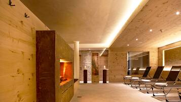 Un spa moderno con paredes de madera, una pared de piedra y una hilera de tumbonas.