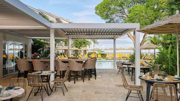 Un patio al aire libre con mobiliario de mimbre, piscina y sombrillas.
