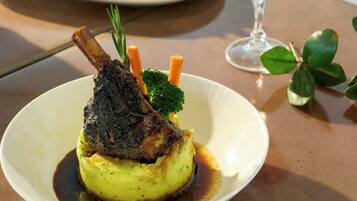 A plate of food with a lamb shank, mashed potatoes, and vegetables.