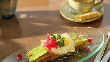 Un plato de desayuno con tostadas, aguacate, un huevo frito y adornos sobre un plato de vidrio.