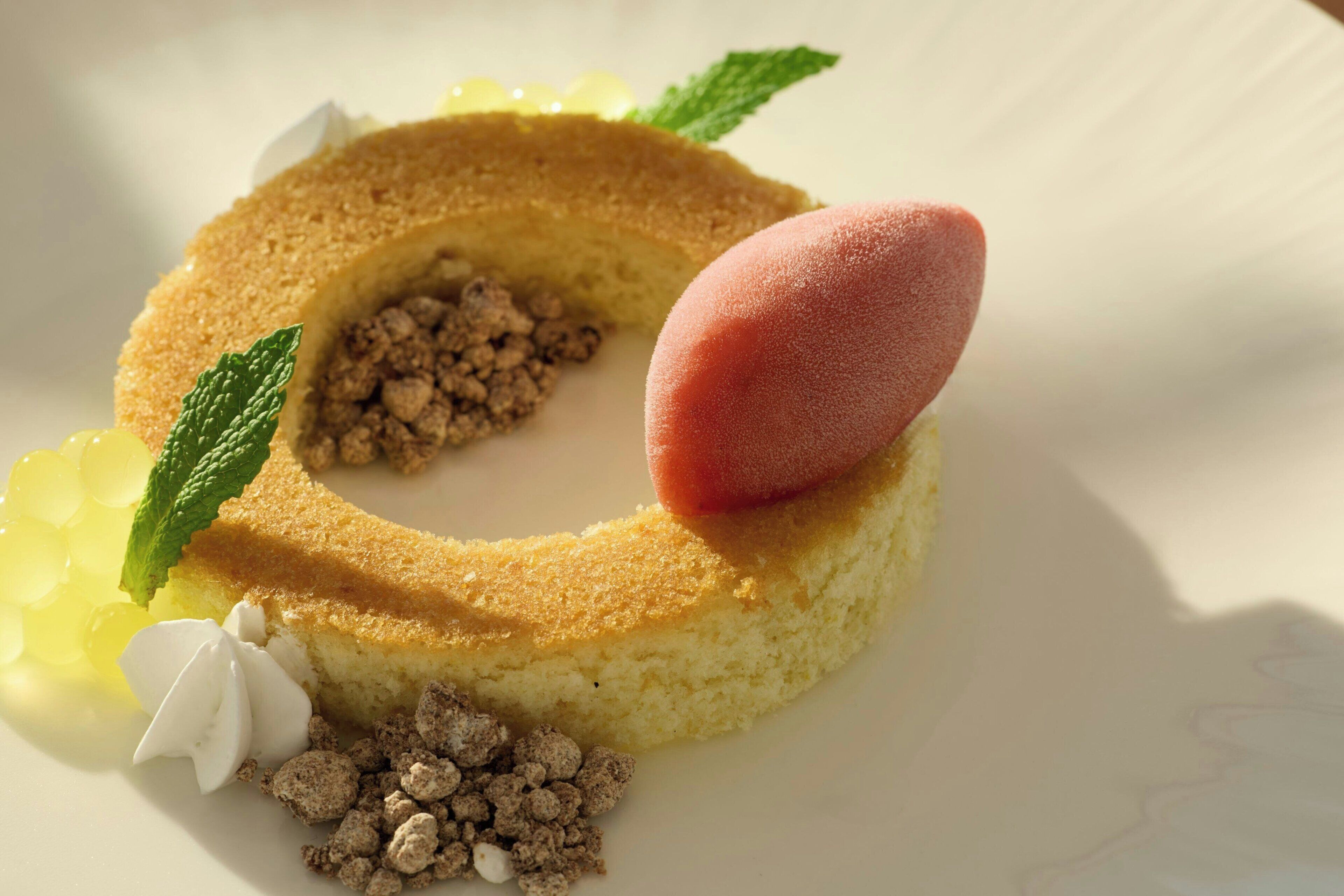 A dessert with a round base, a dollop of cream, and a mint leaf.