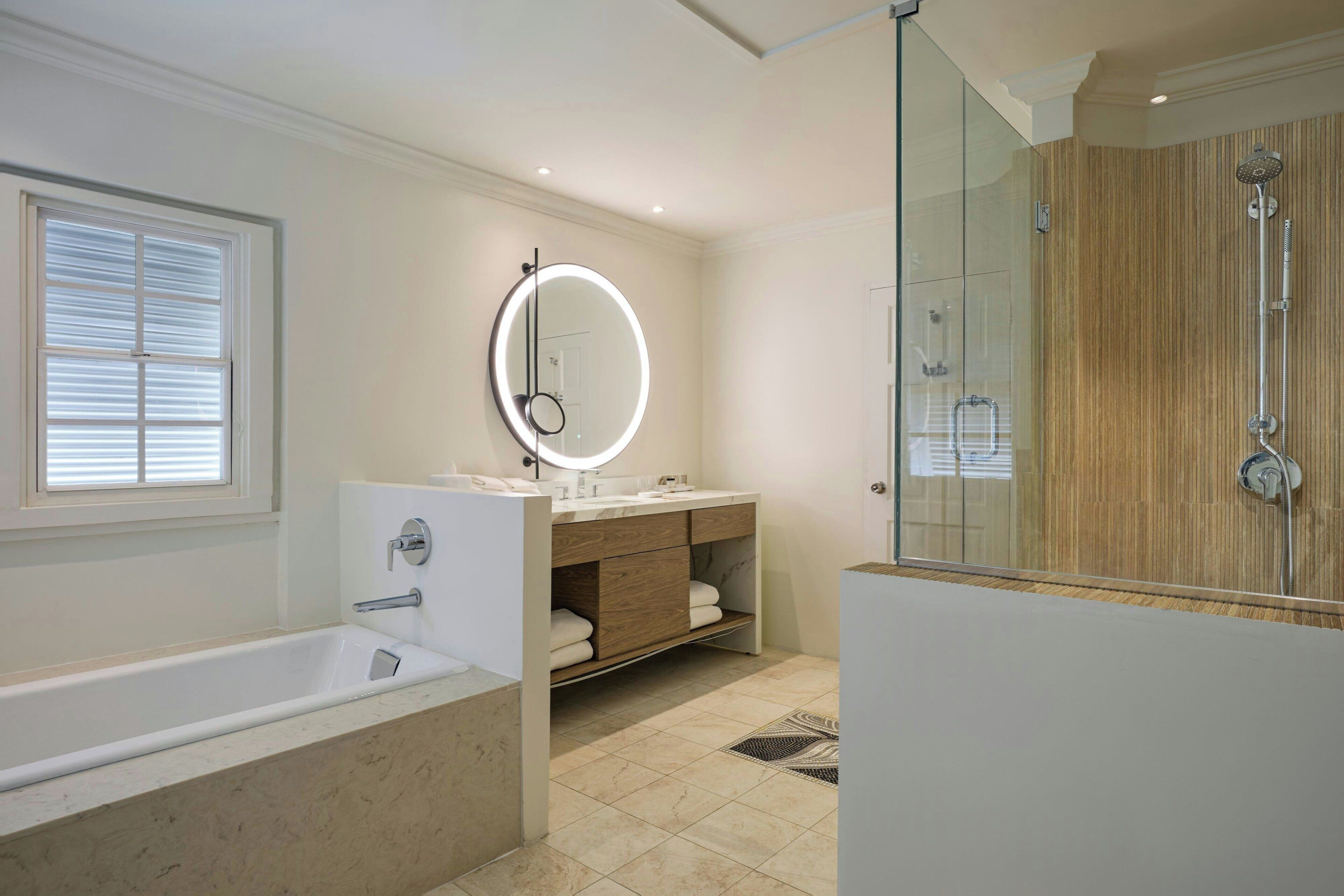 Een moderne badkamer met een badkuip, een wastafel met spiegel en een douche.