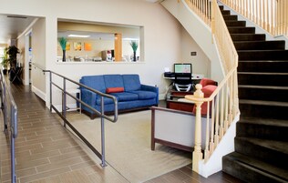 A hotel lobby with a blue sofa, a desk with a computer, and a staircase.