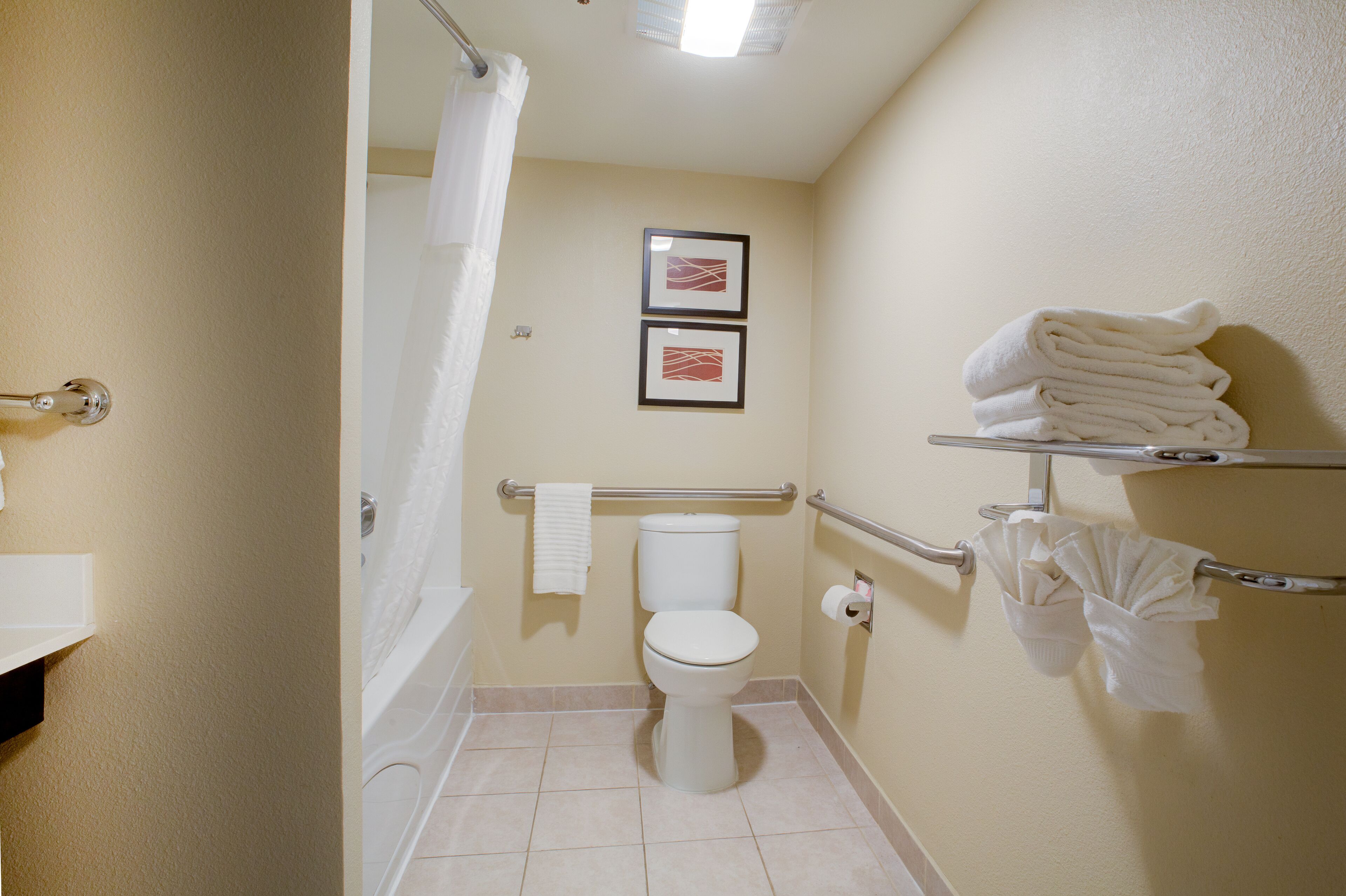 A bathroom with a toilet, a bathtub, a shower curtain, and a towel rack with towels.