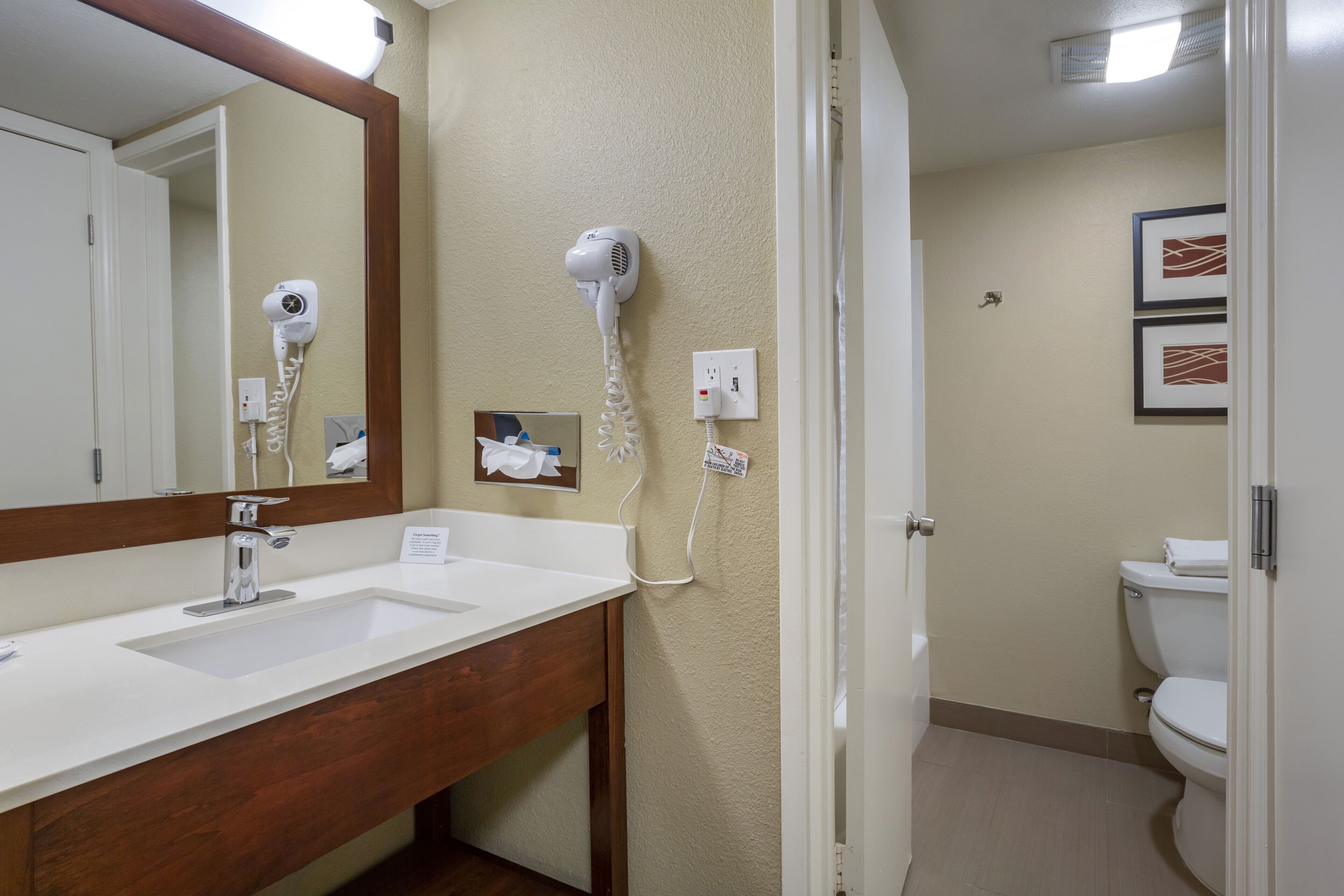 A bathroom with a white sink, a mirror, a hairdryer, and a toilet.