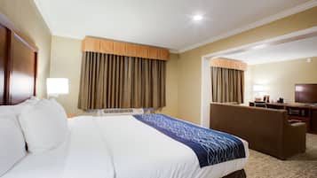 A hotel room with a large bed, a desk, a chair, a television, and curtains.