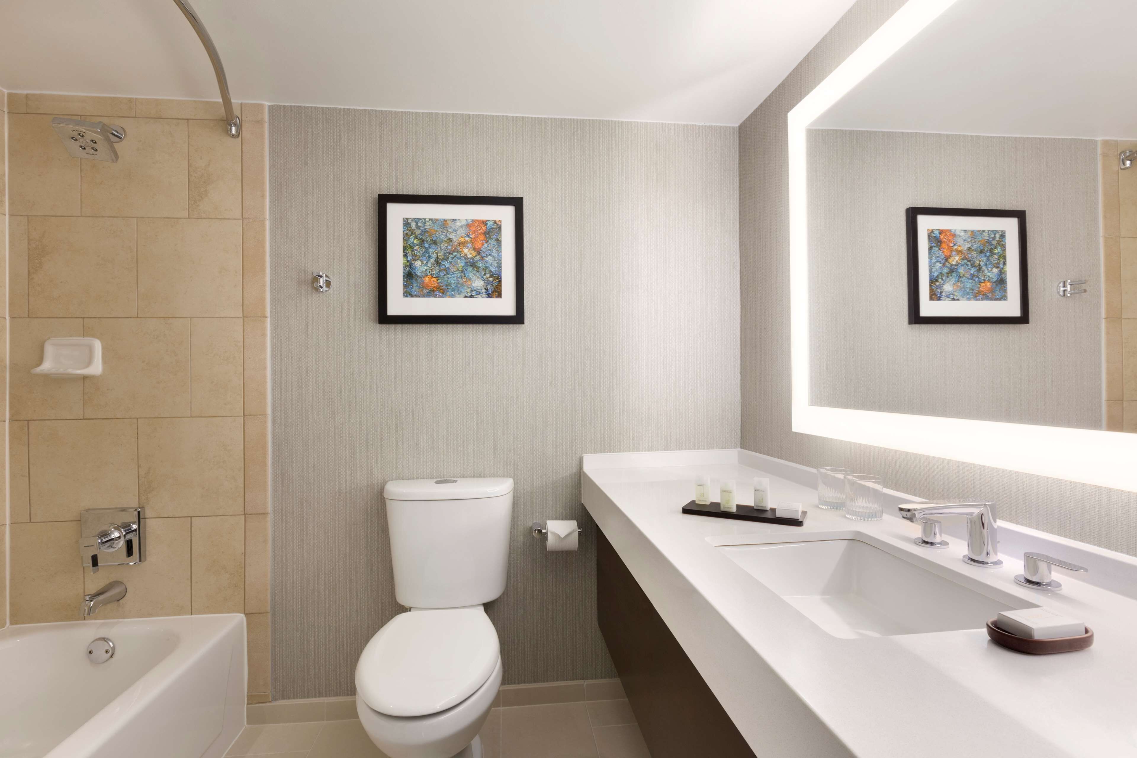 A modern bathroom with a bathtub, toilet, and a large mirror above the sink.