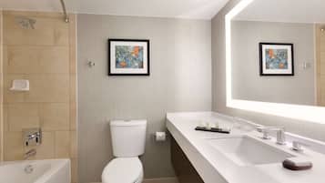 A modern bathroom with a bathtub, toilet, and a large mirror above the sink.