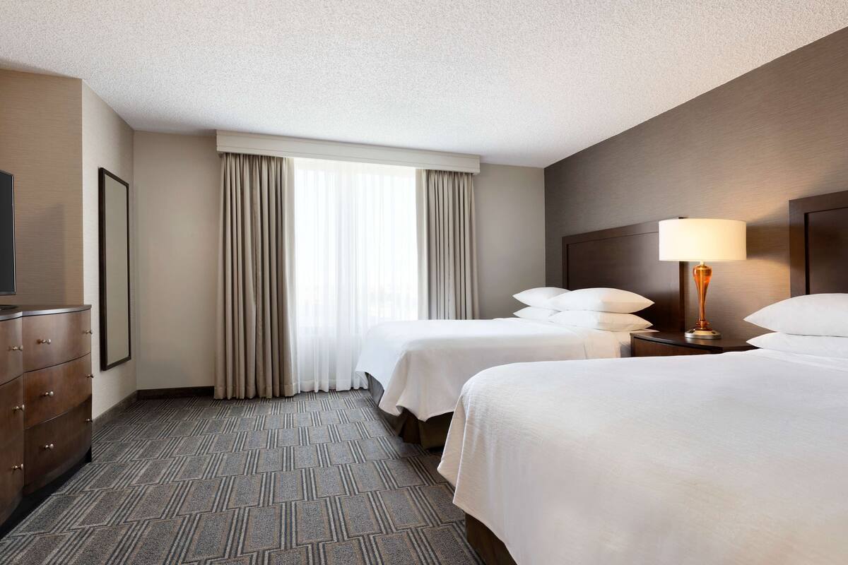 Une chambre d’hôtel avec deux lits, une commode, un téléviseur et une lampe.