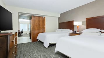 A hotel room with two beds, a desk, a TV, and a wardrobe.
