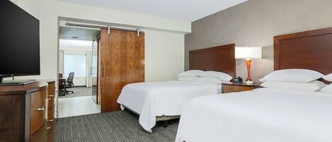 A hotel room with two beds, a desk, a TV, and a wardrobe.