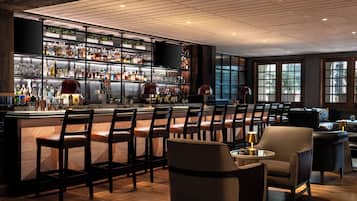 A bar area with multiple seating options, a well-stocked liquor shelf, and large windows providing natural light.
