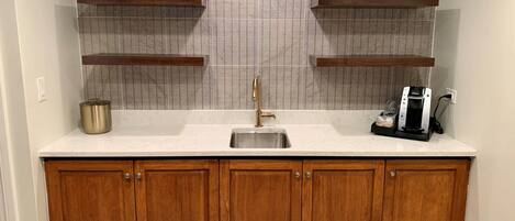 A kitchen with wooden cabinets, a stainless steel sink, and a coffee maker.