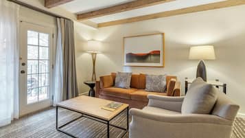 Una sala de estar con sofá, sillón, mesa de centro, lámpara de pie y un cuadro en la pared.