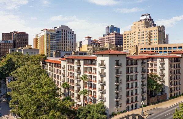 A multi-story hotel with a central courtyard, featuring balconies and a clock tower. - Omni La Mansion del Rio (San Antonio)