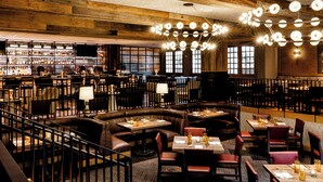 A restaurant with wooden ceiling beams, leather booths, and tables with candles. - Omni La Mansion del Rio (San Antonio)