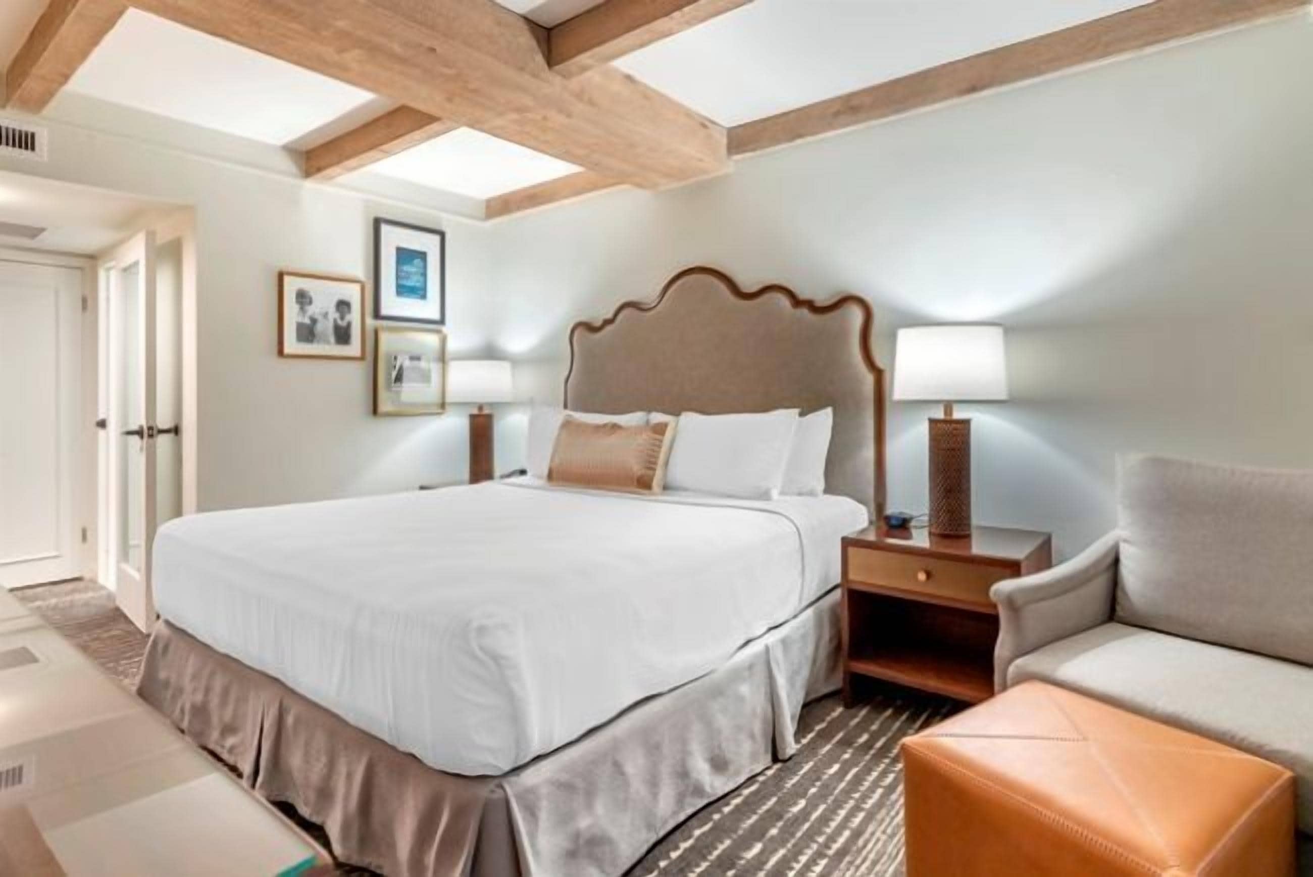 A hotel room with a large bed, bedside tables, a sofa, and a patterned rug.