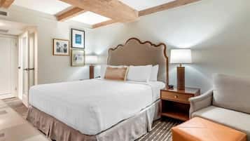 A hotel room with a large bed, bedside tables, a sofa, and a patterned rug.