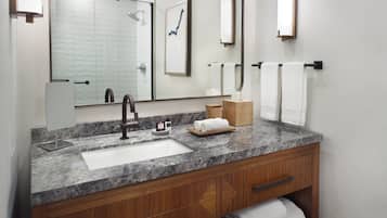 A bathroom with a marble sink, wooden vanity, and a large mirror.