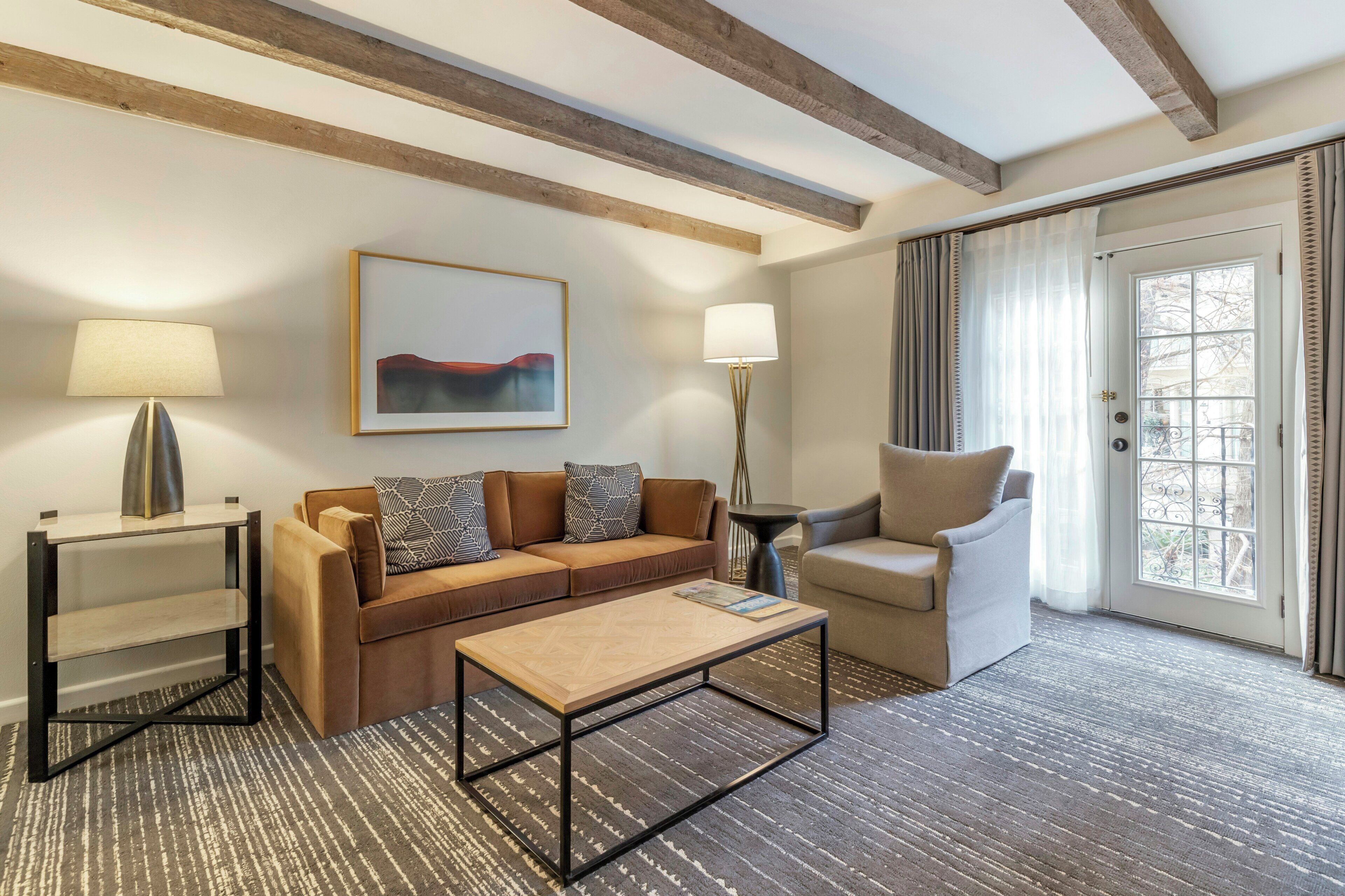 Una sala moderna con sofá, sillón, mesa de centro y lámparas.