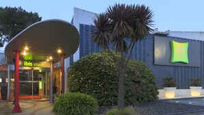 Entrada de hotel con diseño moderno, incluyendo una estructura de techo curva y fachada de vidrio.