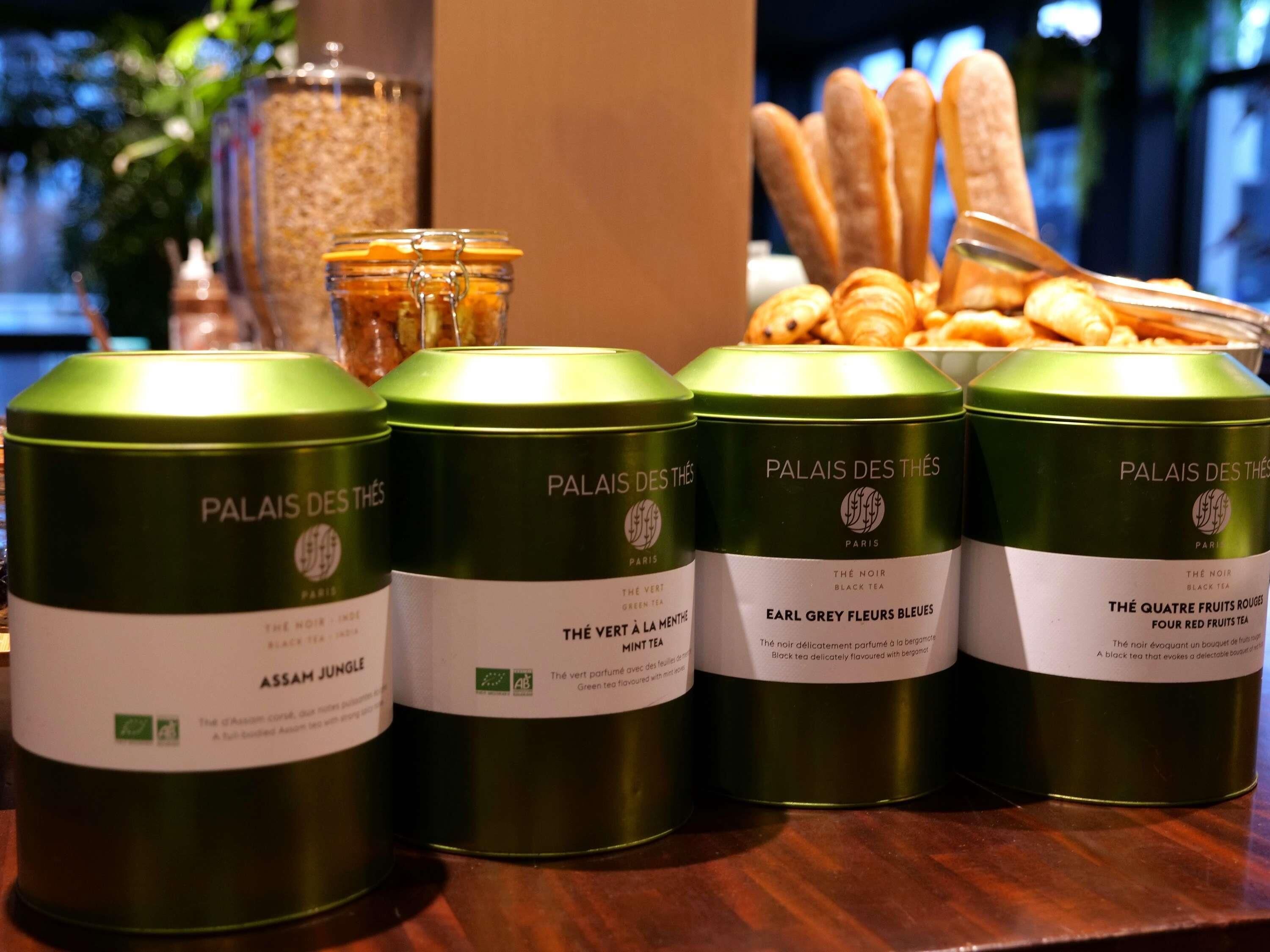 Cuatro latas de té verde etiquetadas como 'Palais des Thés', con diferentes variedades de té.