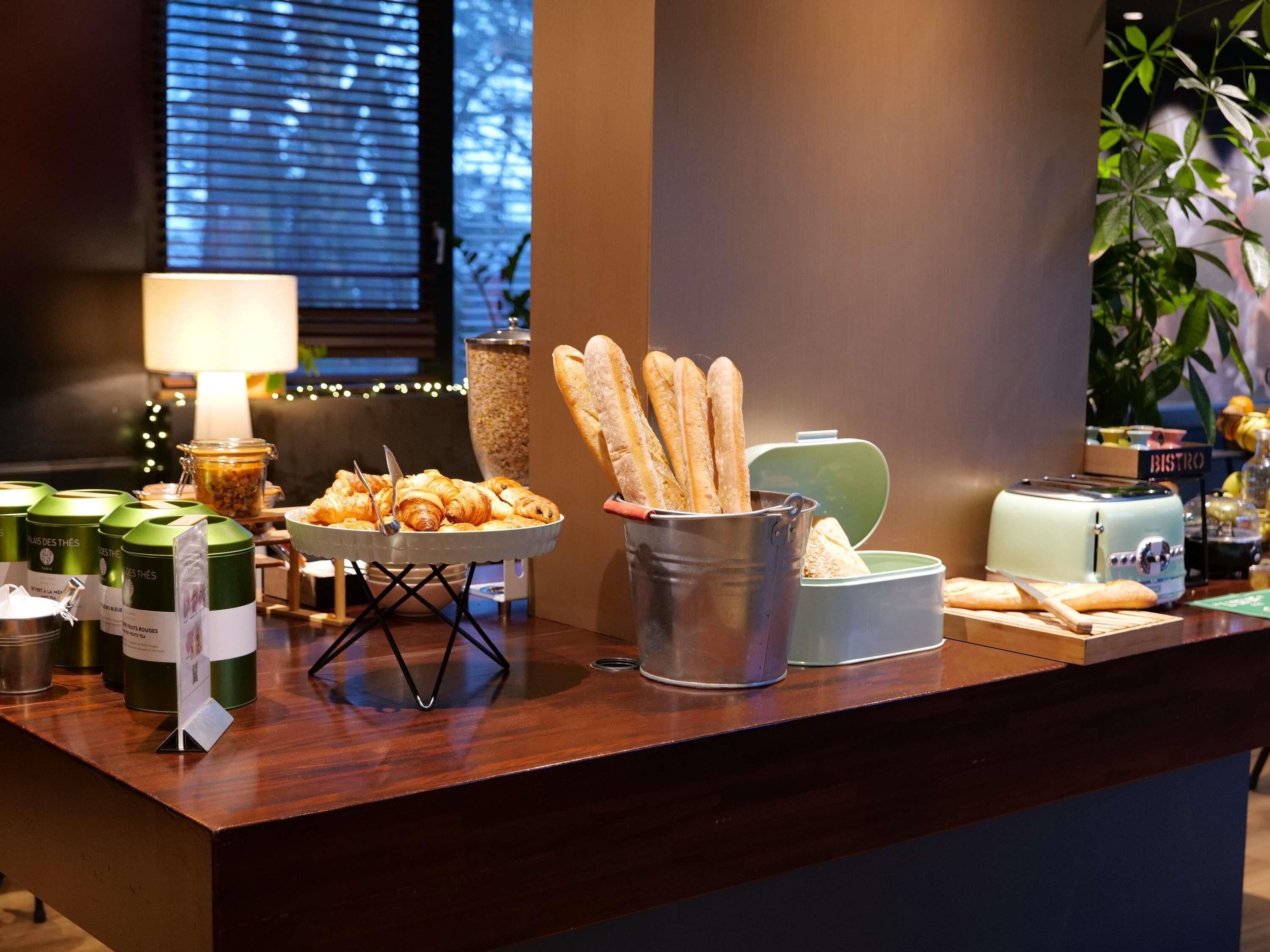 A breakfast buffet with croissants, bread, and a toaster.