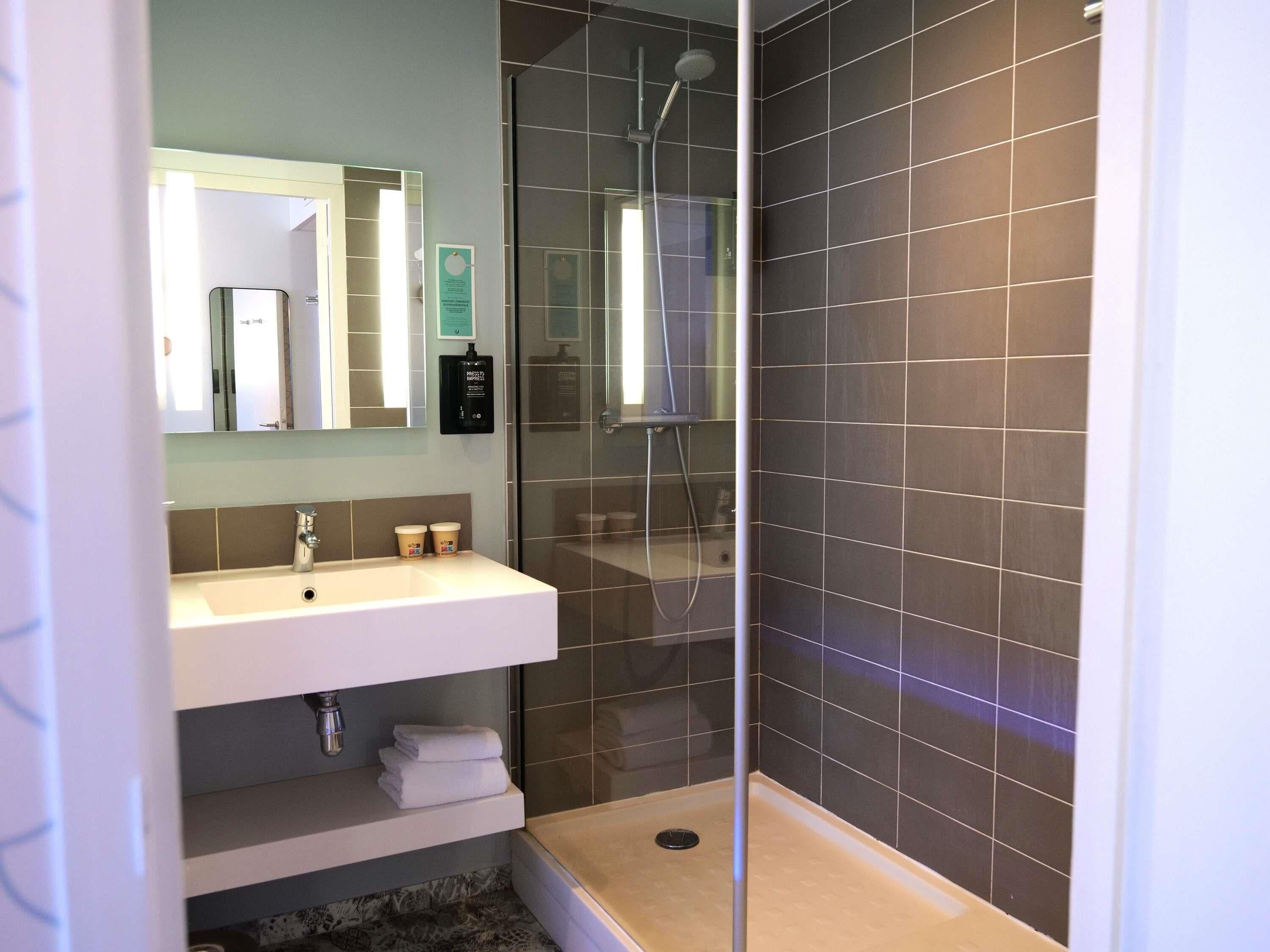 A modern bathroom with a shower, a sink, and a mirror.