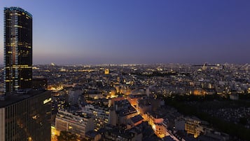 A cityscape at dusk with illuminated buildings and a prominent skyscraper.