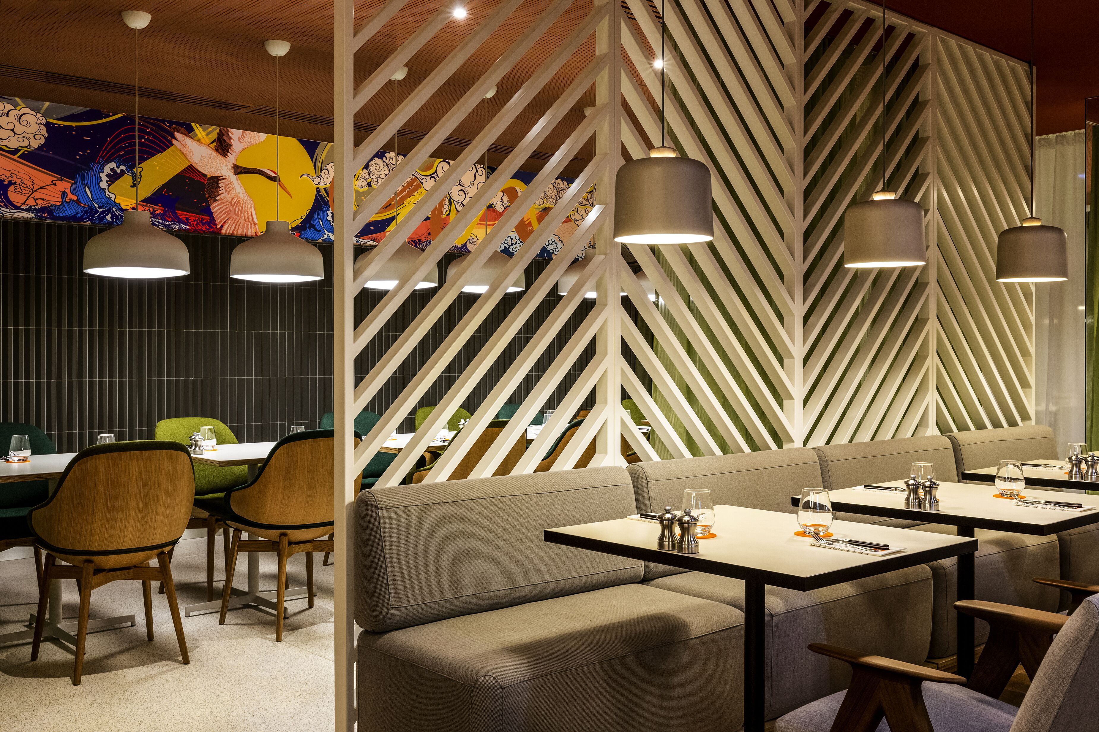 A restaurant with booths and tables, wooden chairs, and hanging pendant lights.