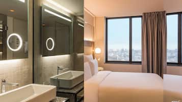 A hotel room with a large bed, a bathroom with a bathtub, a mirror with a ring light, and a city view through the window.