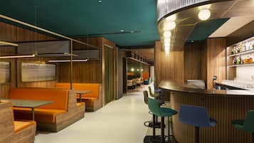A modern bar area with wooden paneling, bar stools, and a counter with bottles.