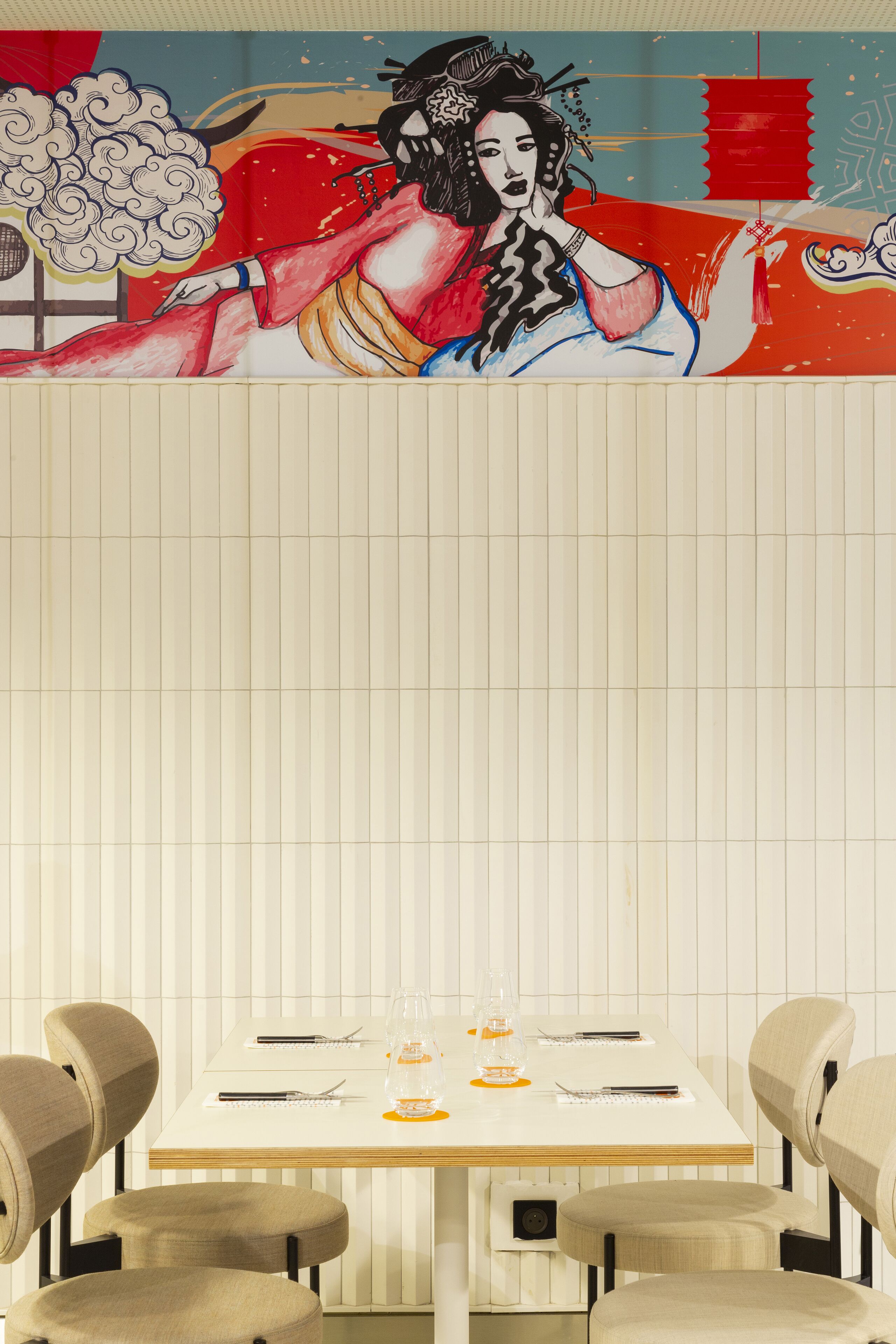 Un coin repas avec une table dressée pour quatre personnes, des chaises et une fresque murale.