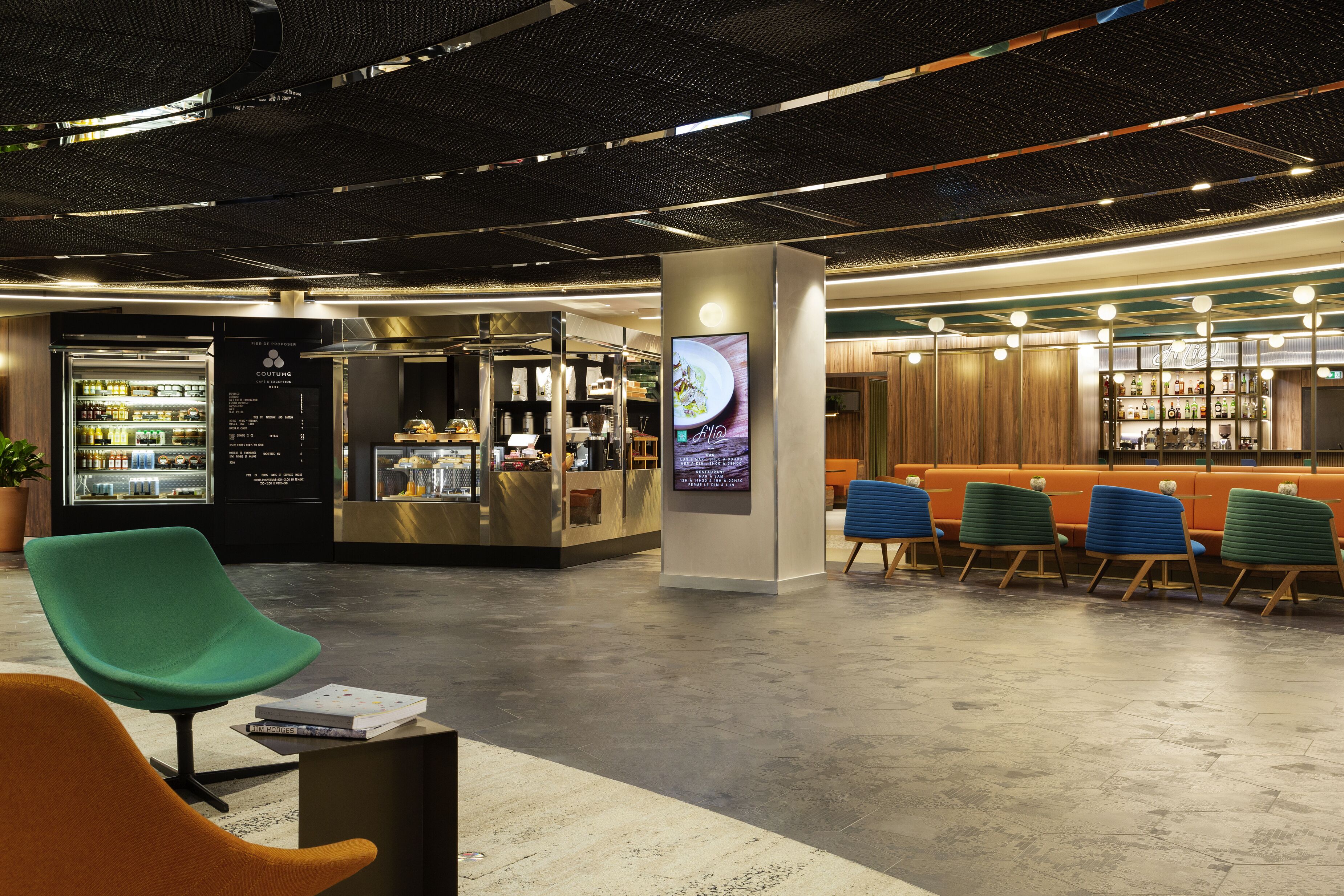 Un hall d’entrée moderne doté d’espaces de détente, d’un bar où l’on sert des boissons et d’un présentoir pour les boissons.