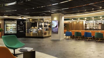 Un hall d’entrée moderne doté d’espaces de détente, d’un bar où l’on sert des boissons et d’un présentoir pour les boissons.