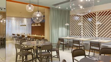 A modern dining area with round tables, chairs, and pendant lighting.