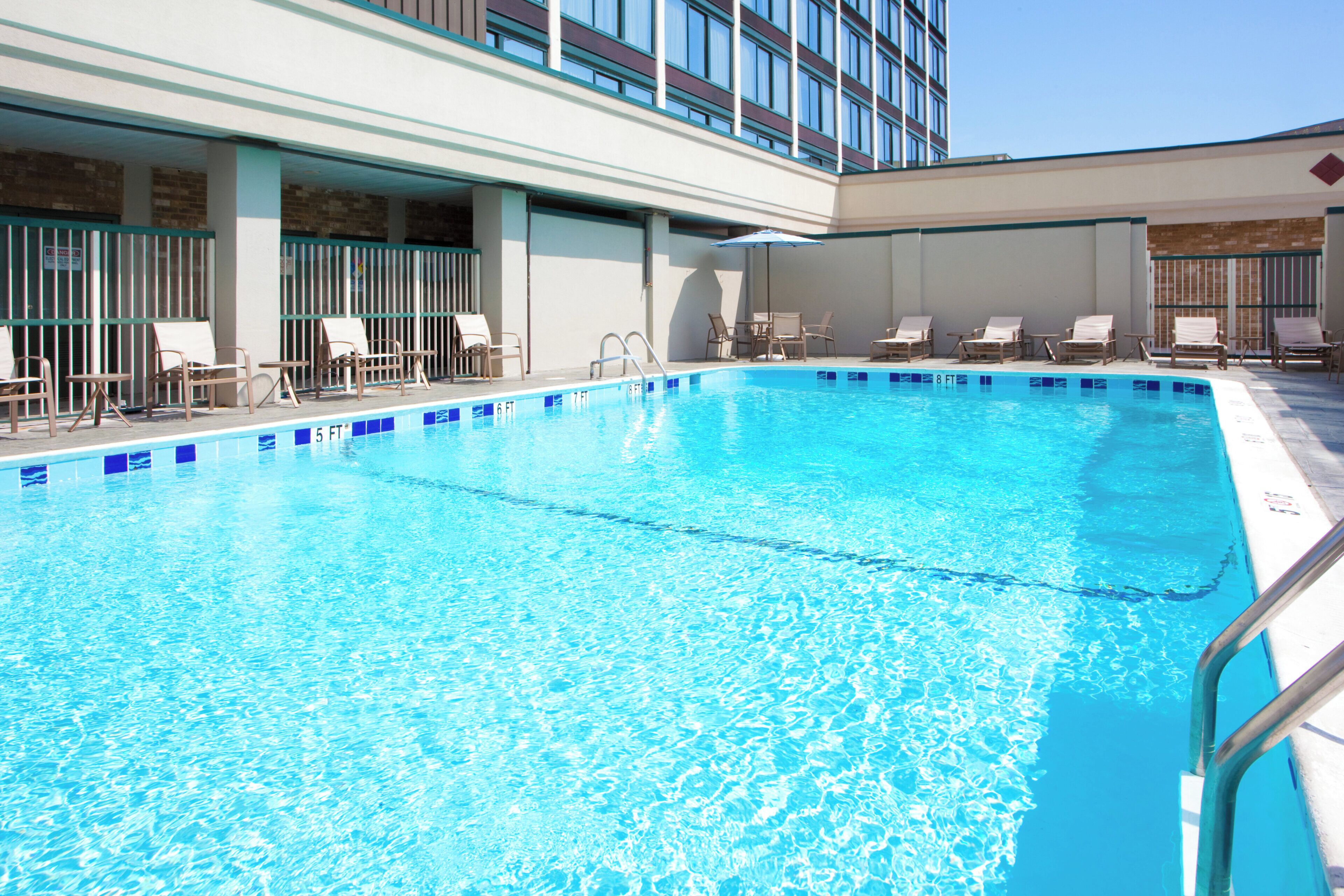A swimming pool with lounge chairs and a covered seating area.