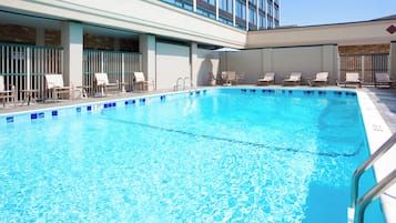 A swimming pool with lounge chairs and a covered seating area.