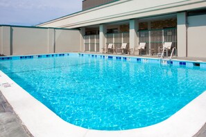 Una piscina al aire libre, sillones reclinables de piscina