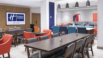 Une salle de conférence de l’hôtel Holiday Inn Express, qui fait partie du groupe IHG, est équipée de tables, de chaises et d’un grand écran affichant le logo de l’hôtel.