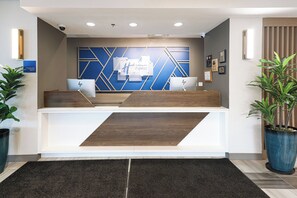 A reception desk with a modern design, featuring a blue and white color scheme and geometric patterns on the wall behind.